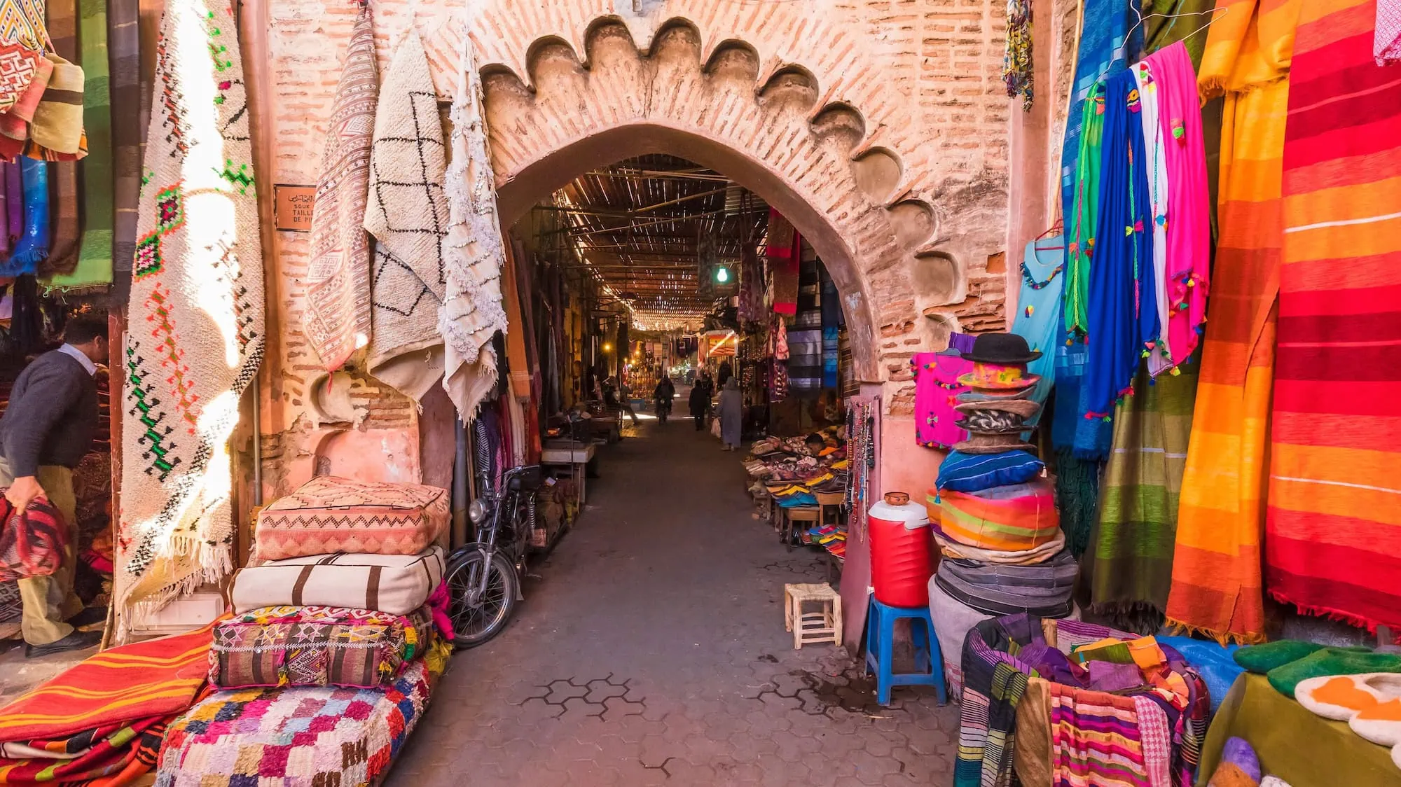 Traditional marketplace in Fez Medina with colorful textiles and arched passageway