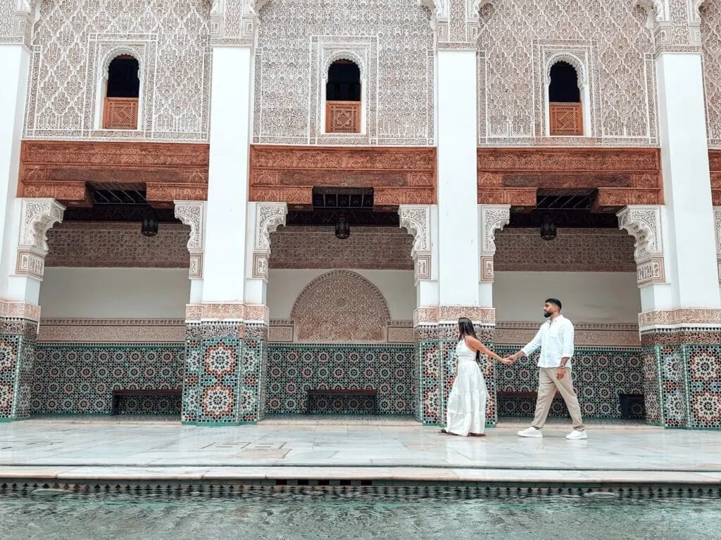 Couple standing in a traditional riad courtyard with tiled walls and arches in Marrakech