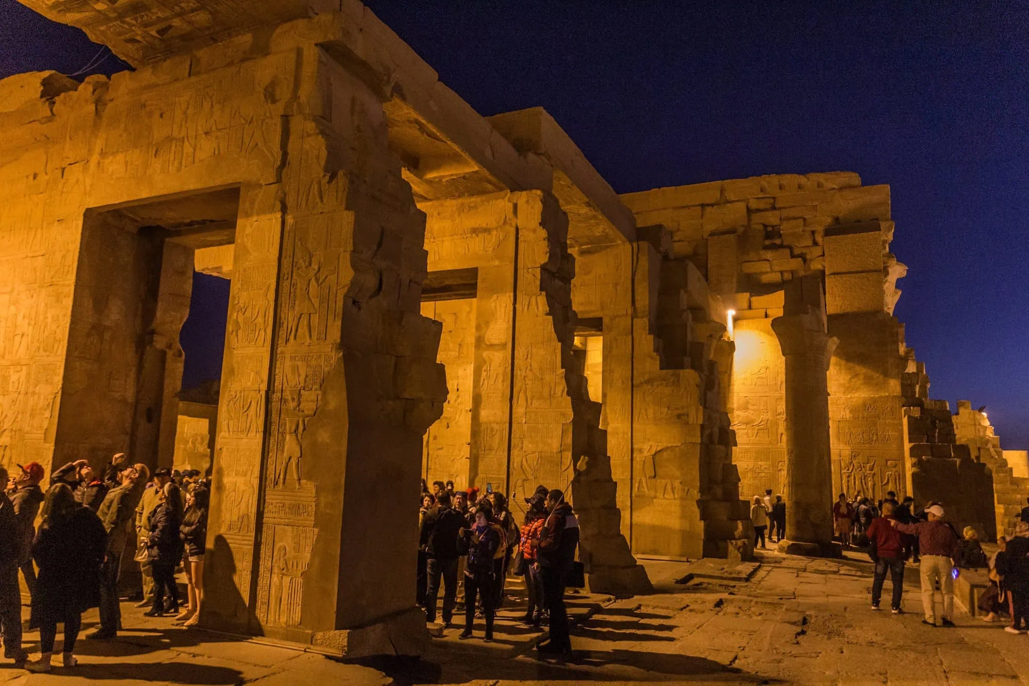 Tourists exploring the illuminated Kom Ombo Temple at dusk during a Nile cruise excursion