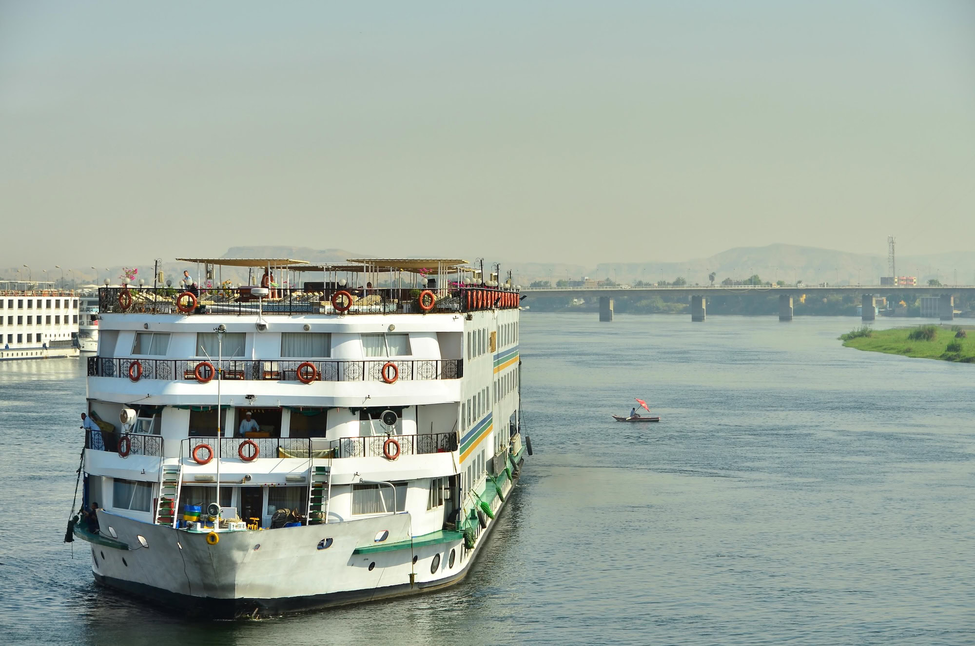 White multi-deck cruise ship docked on the Nile River in Luxor