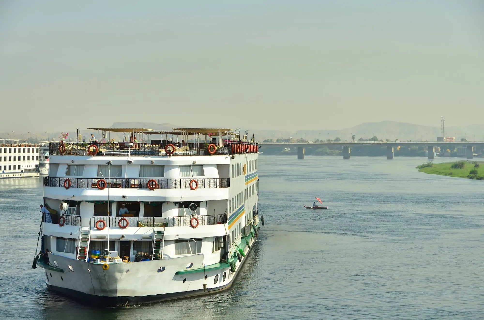 White multi-deck cruise ship docked on the Nile River in Luxor