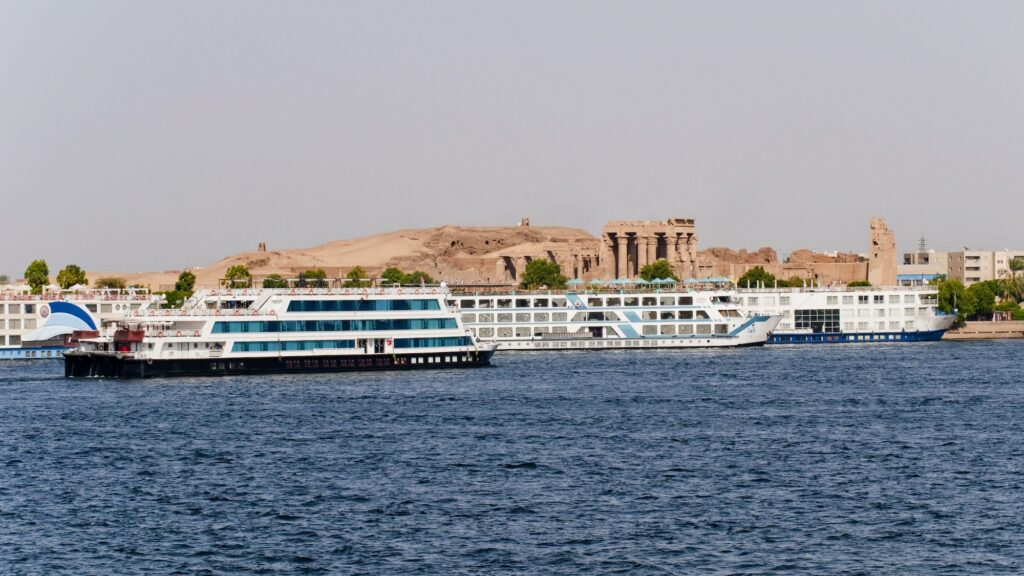 Cruise ships docked along the Nile River with the Temple of Kom Ombo visible on the riverbank at Kom Ombo, Kom Ombo