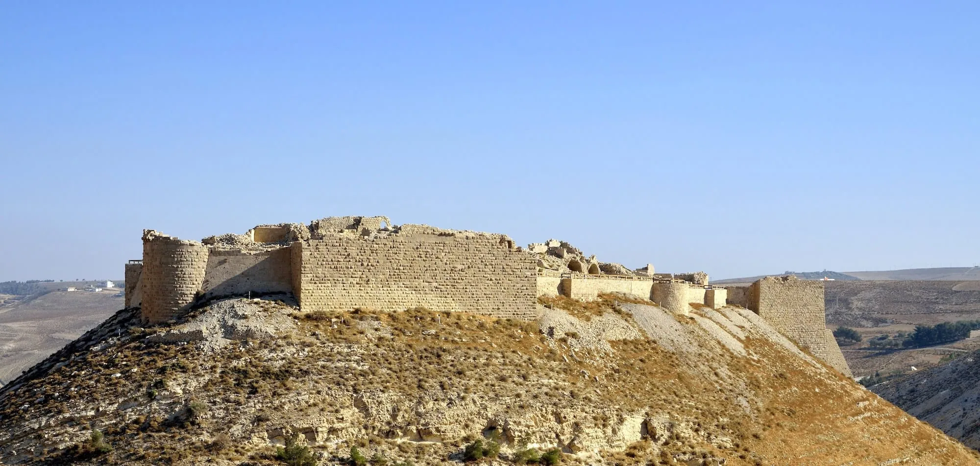 Ancient Crusader castle ruins on hilltop in desert landscape