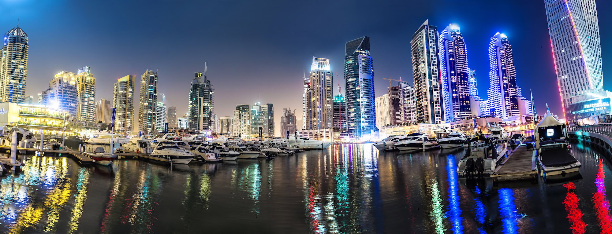 Dubai Marina with illuminated skyscrapers and luxury yachts at dusk
