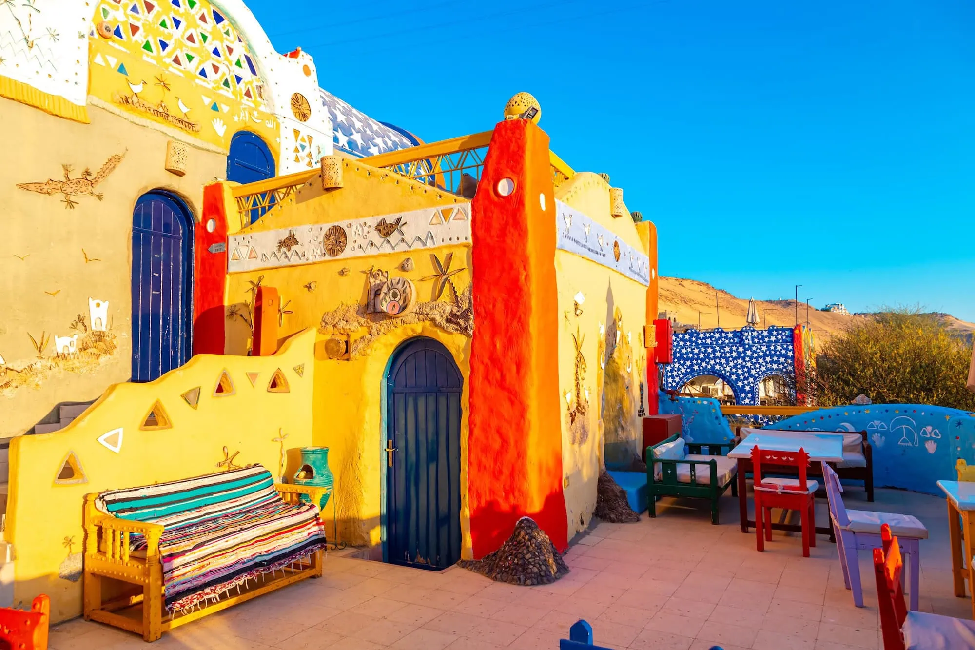 Colorful traditional Nubian village building with decorative murals and striped outdoor seating