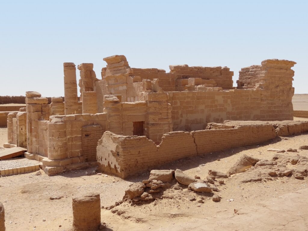 Stone temple ruins with standing walls and columns at Deir el-Hagar Temple in the desert landscape, Dakhla Oasis