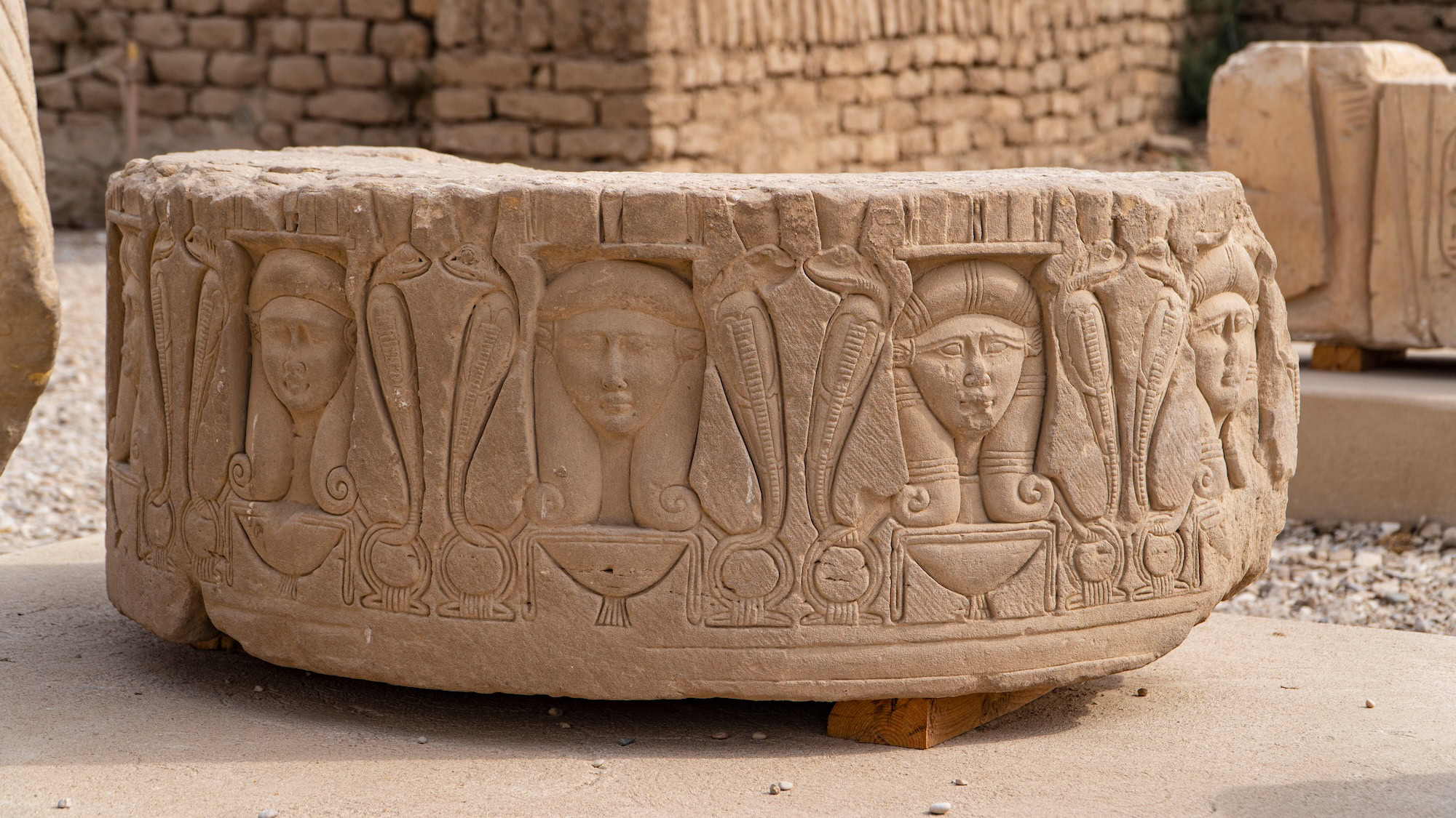 Ancient Egyptian stone column with carved hieroglyphs and pharaoh reliefs