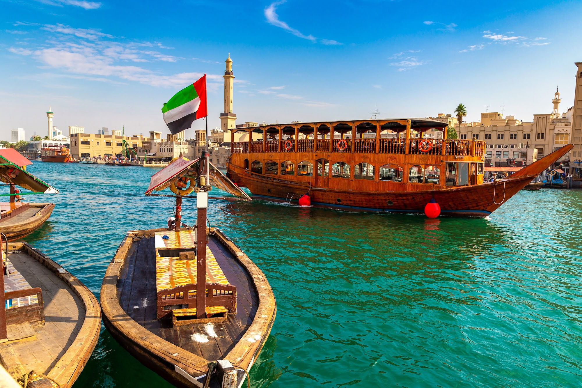 Traditional dhow boats on Dubai Creek waterfront with historic buildings