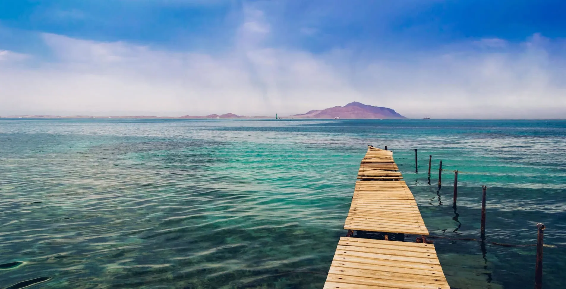 Dilapidated Pier in the Red Sea. Tiran Island on Backdrop