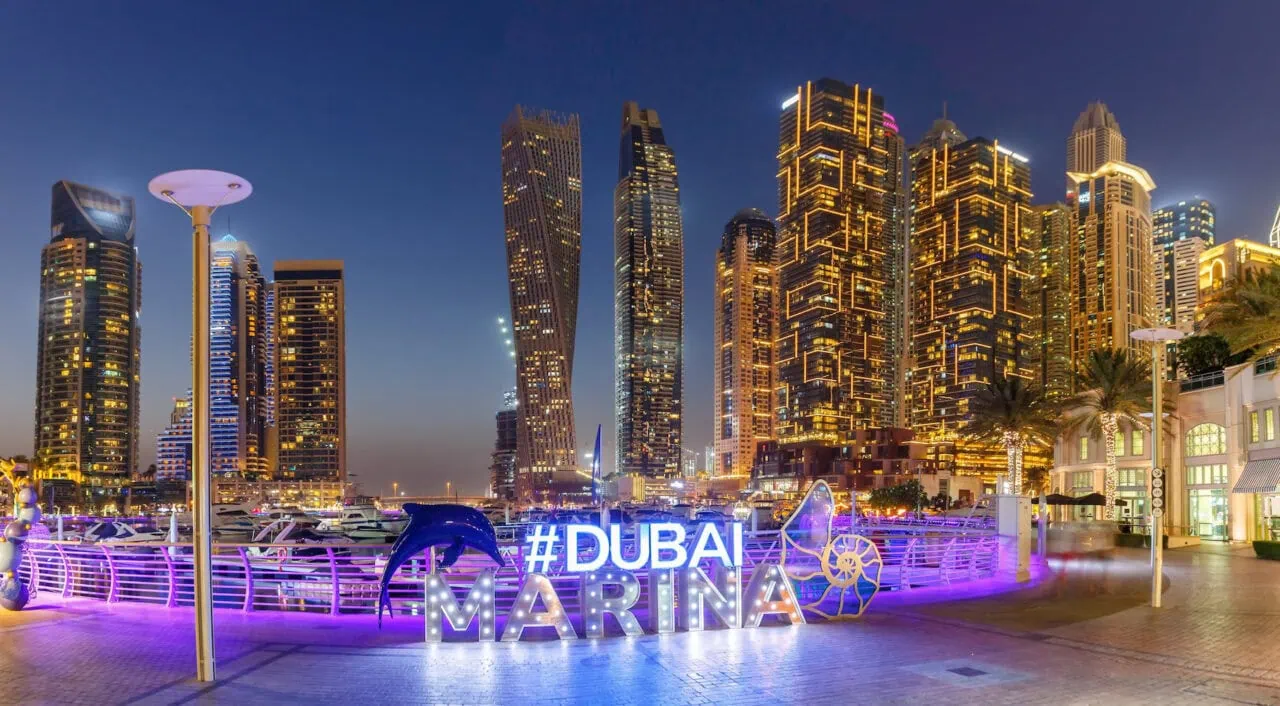 Dubai Marina logo and Harbour skyline architecture wealth luxury travel panorama at night in United Arab Emirates modern