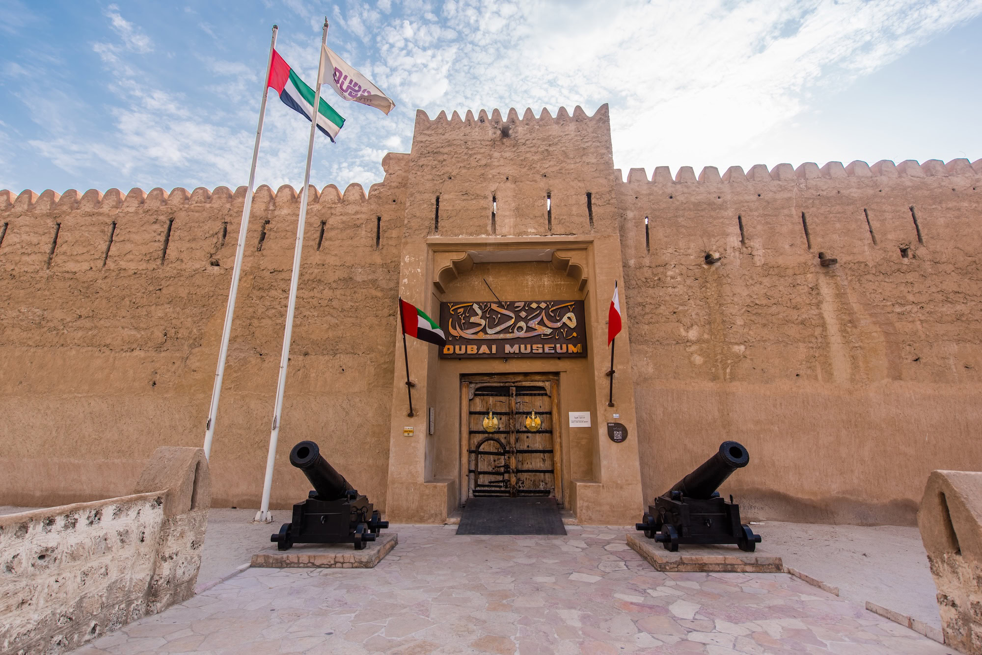 Historic Dubai Museum entrance with traditional wooden doors, stone walls, and courtyard at Al Fahidi Fort