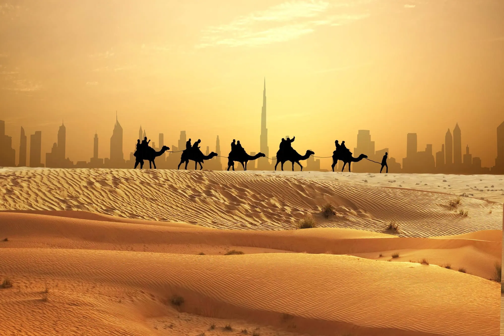 Camel caravan in desert with Dubai skyline featuring Burj Khalifa