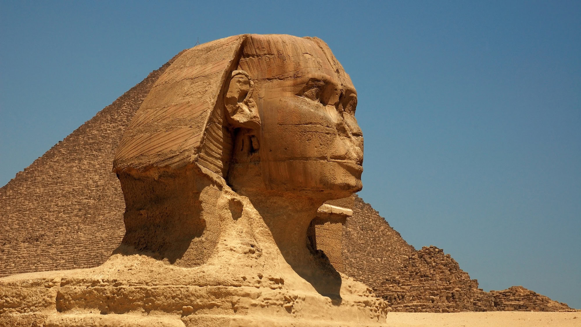 The Great Sphinx of Giza with pyramid in background showcasing ancient Egyptian monuments