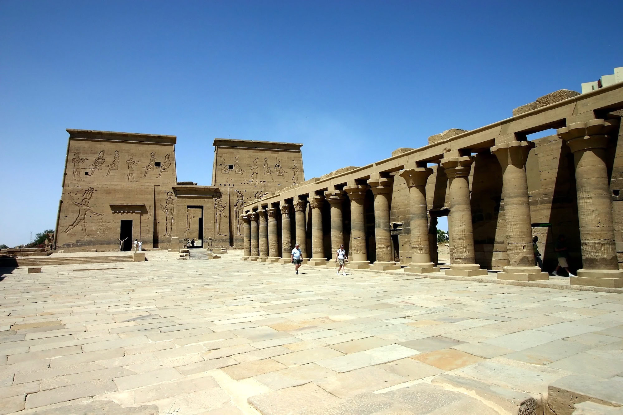 Tourists exploring ancient Philae Temple with towering columns and hieroglyphic walls