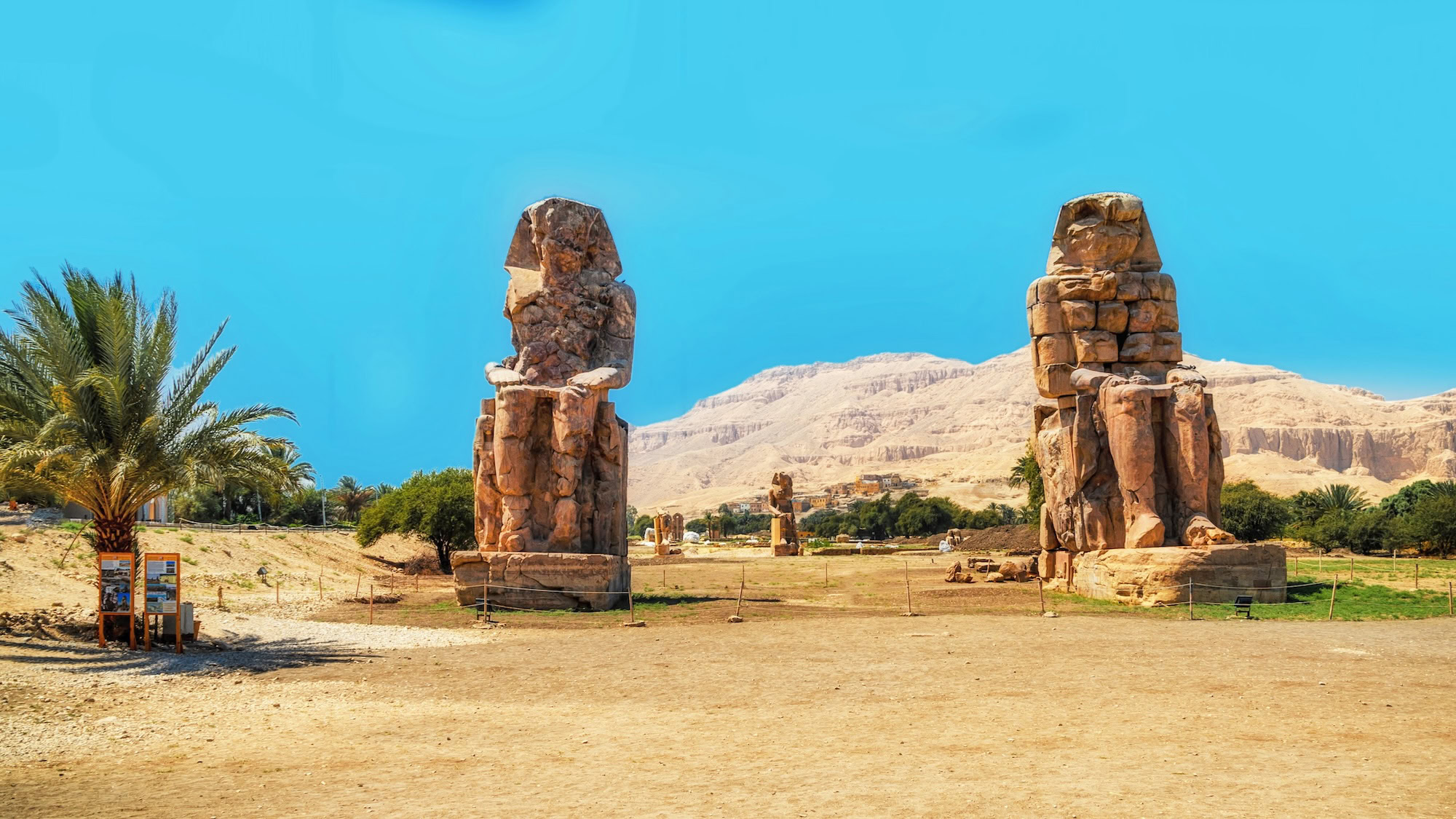The ancient Colossi of Memnon statues standing as guardians in the Egyptian desert landscape