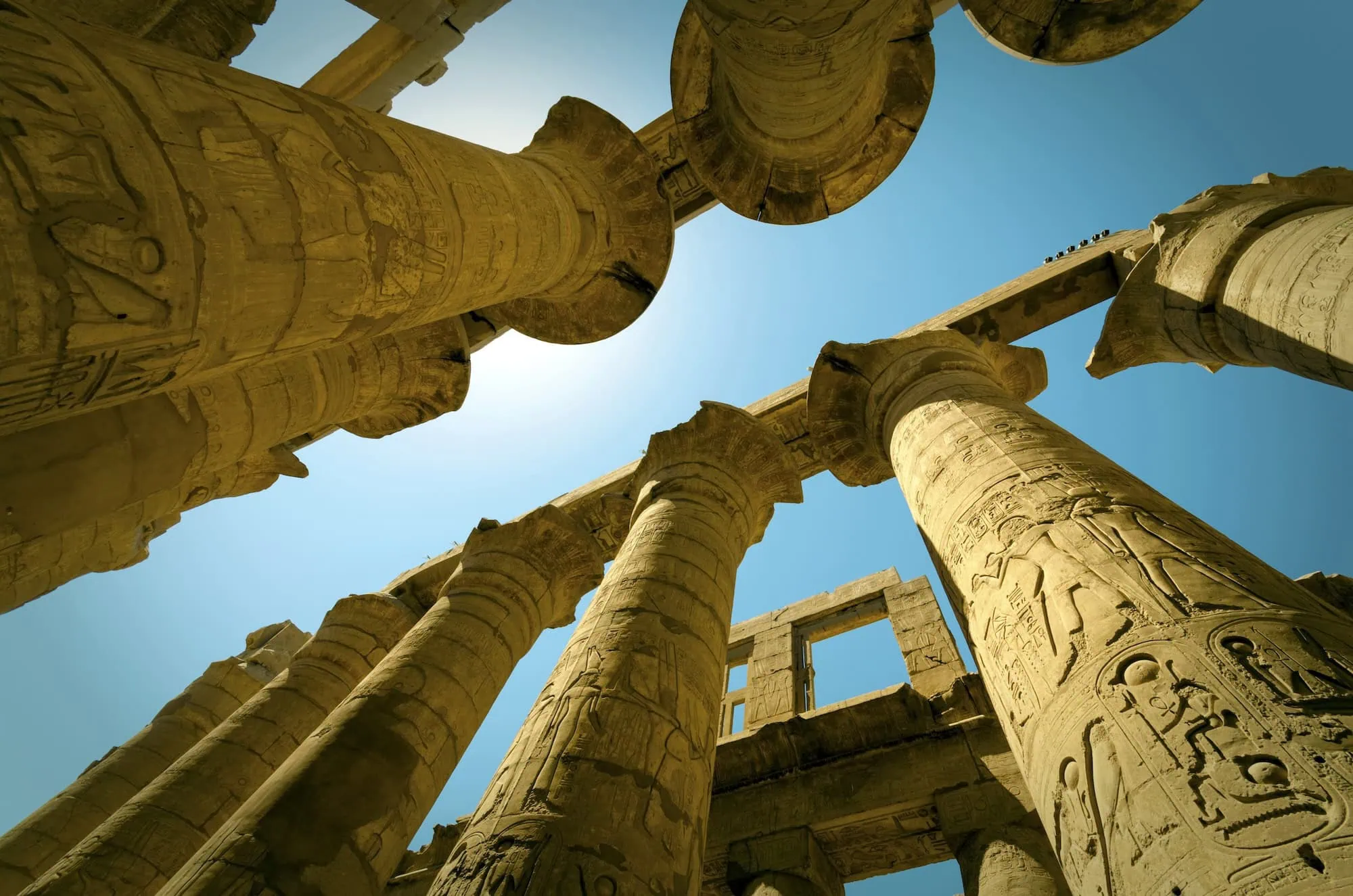 Massive ancient Egyptian columns with hieroglyphic carvings and papyrus capitals at Karnak Temple's Great Hypostyle Hall