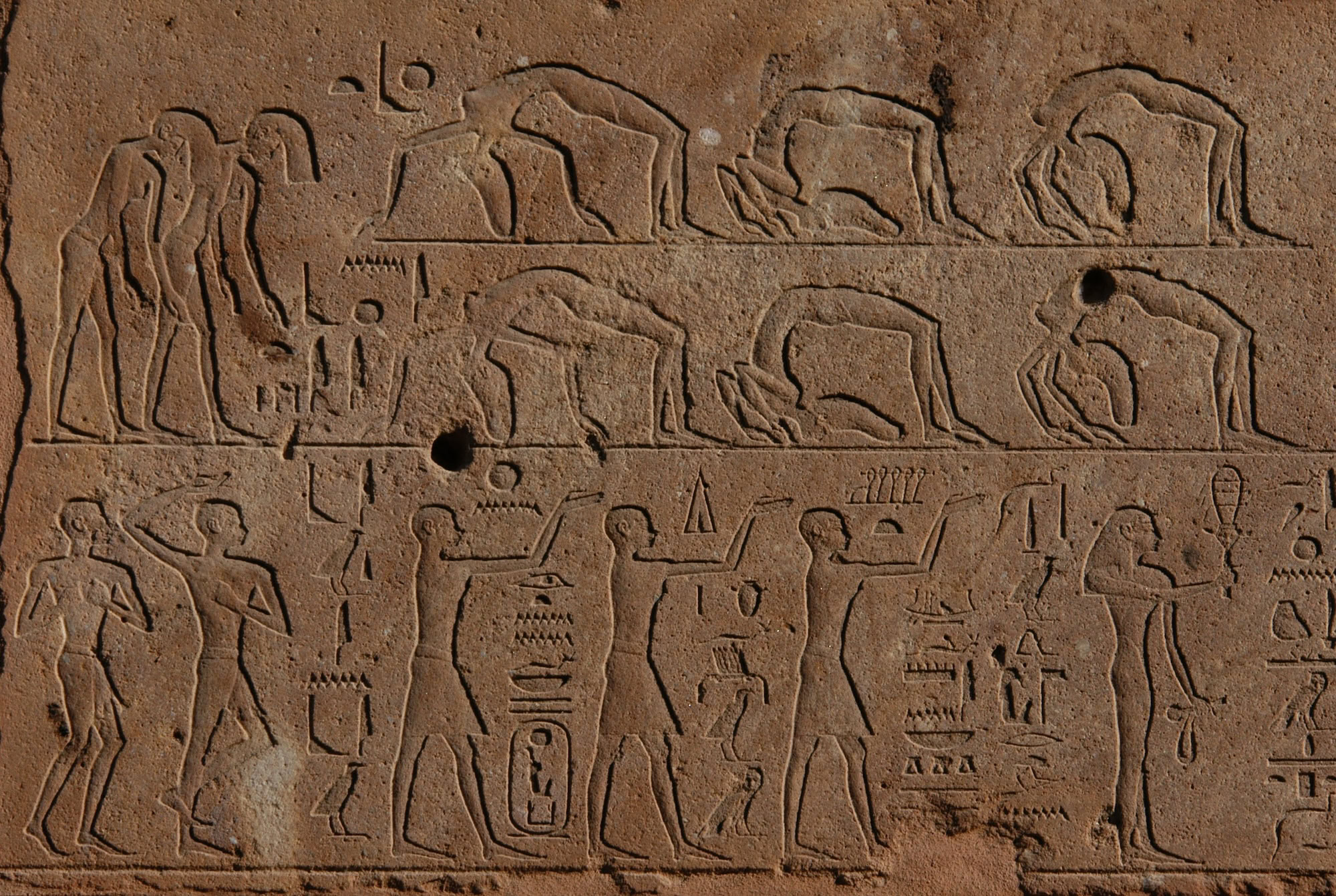 Ancient Egyptian temple wall with hieroglyphic carvings and stone columns in golden light