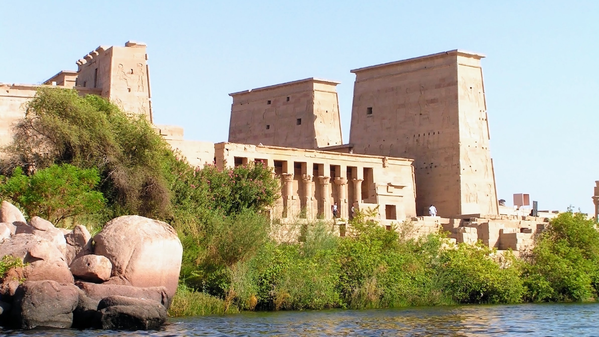 Ancient Egyptian temple with palm trees and water in warm outdoor setting