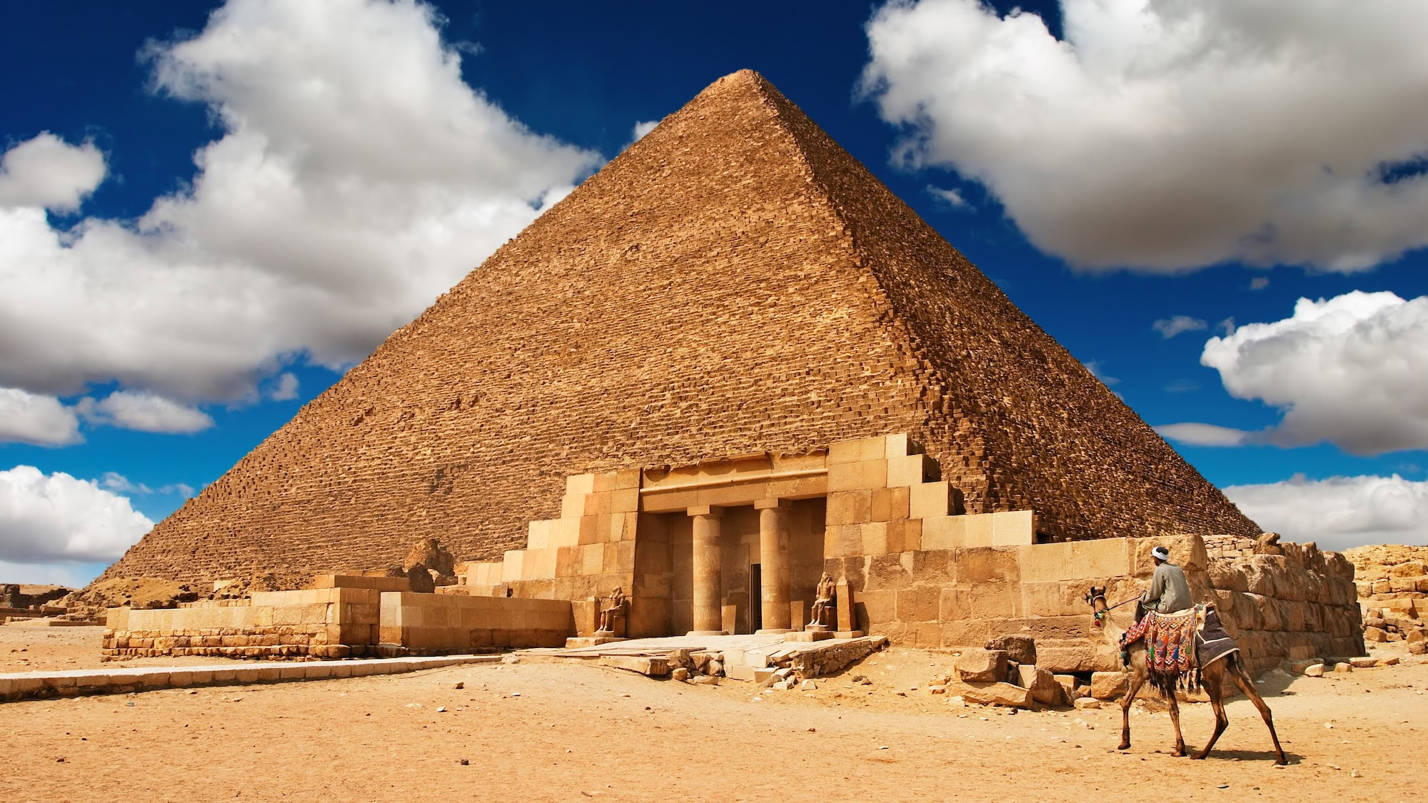 Tourists with camels at the Great Pyramid of Giza in desert landscape