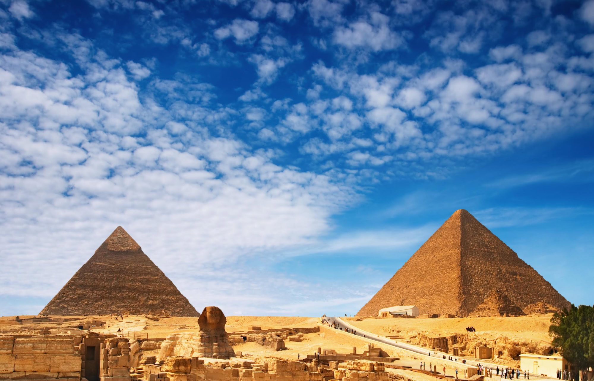 Panoramic view of Giza pyramid complex with Great Sphinx and pyramids under blue sky