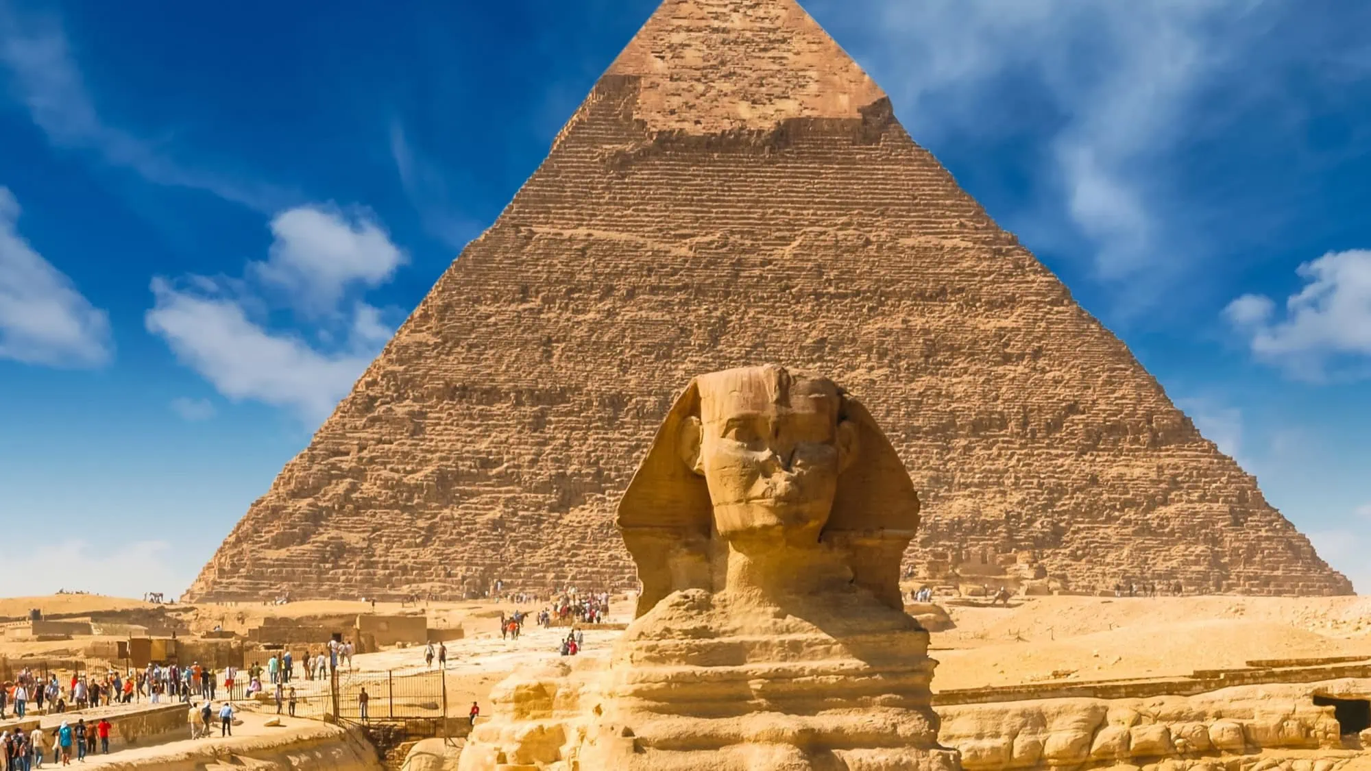 Great Sphinx of Giza with pyramid in background and tourists visiting