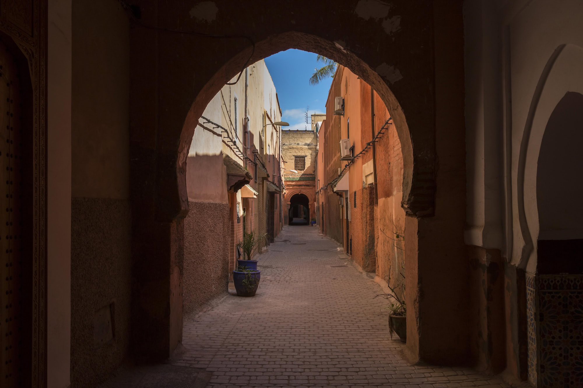 Traditional narrow alleyway in Marrakech medina with archways and cobblestone streets