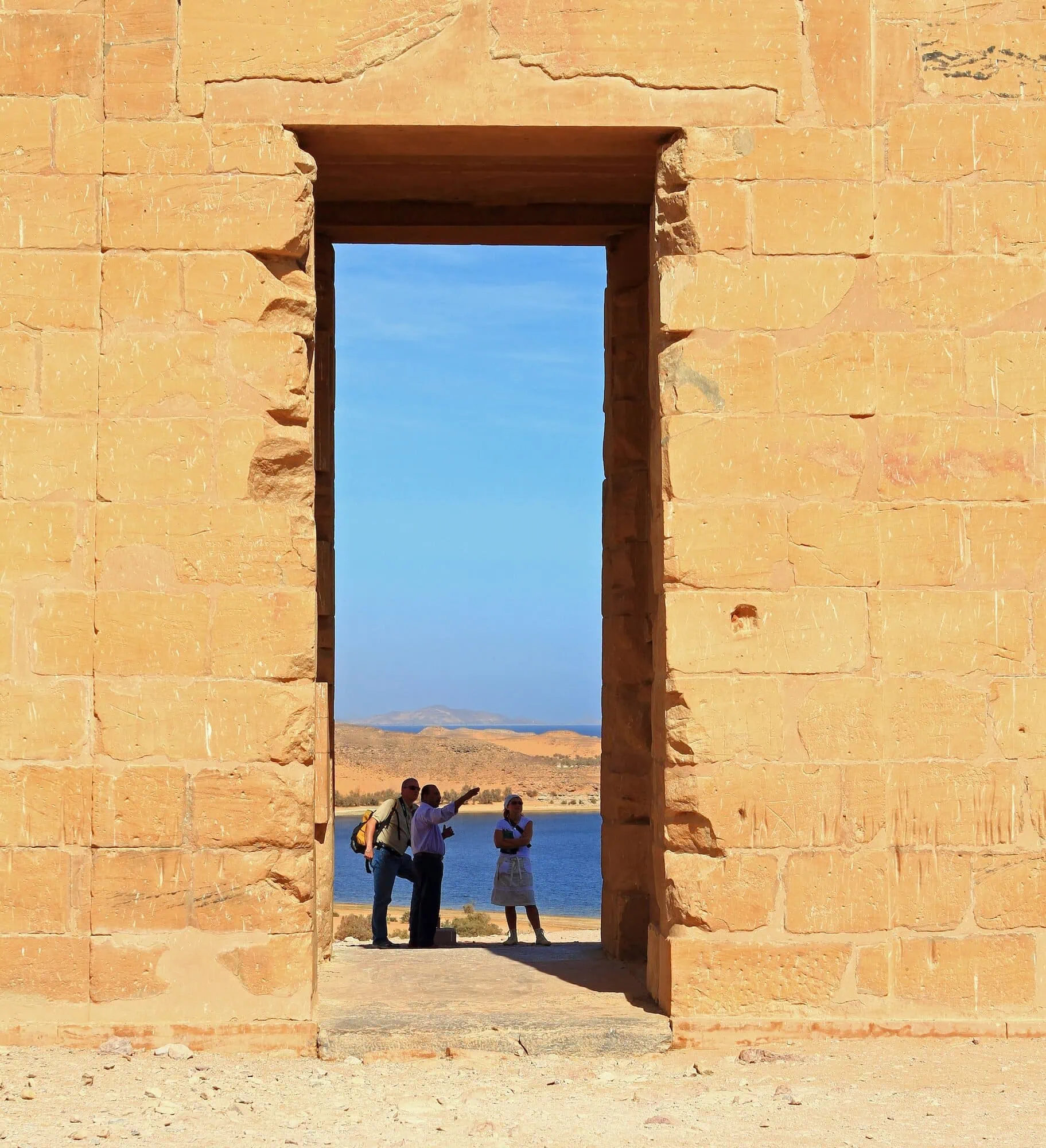 Tourists visiting ancient Egyptian temple ruins in desert landscape
