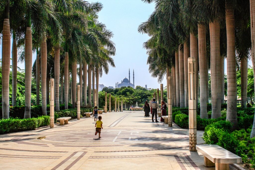 Families having fun in Al Azhar Park in Cairo. Child running in the alley. Silhouette of the Citadel of Saladin in the background.