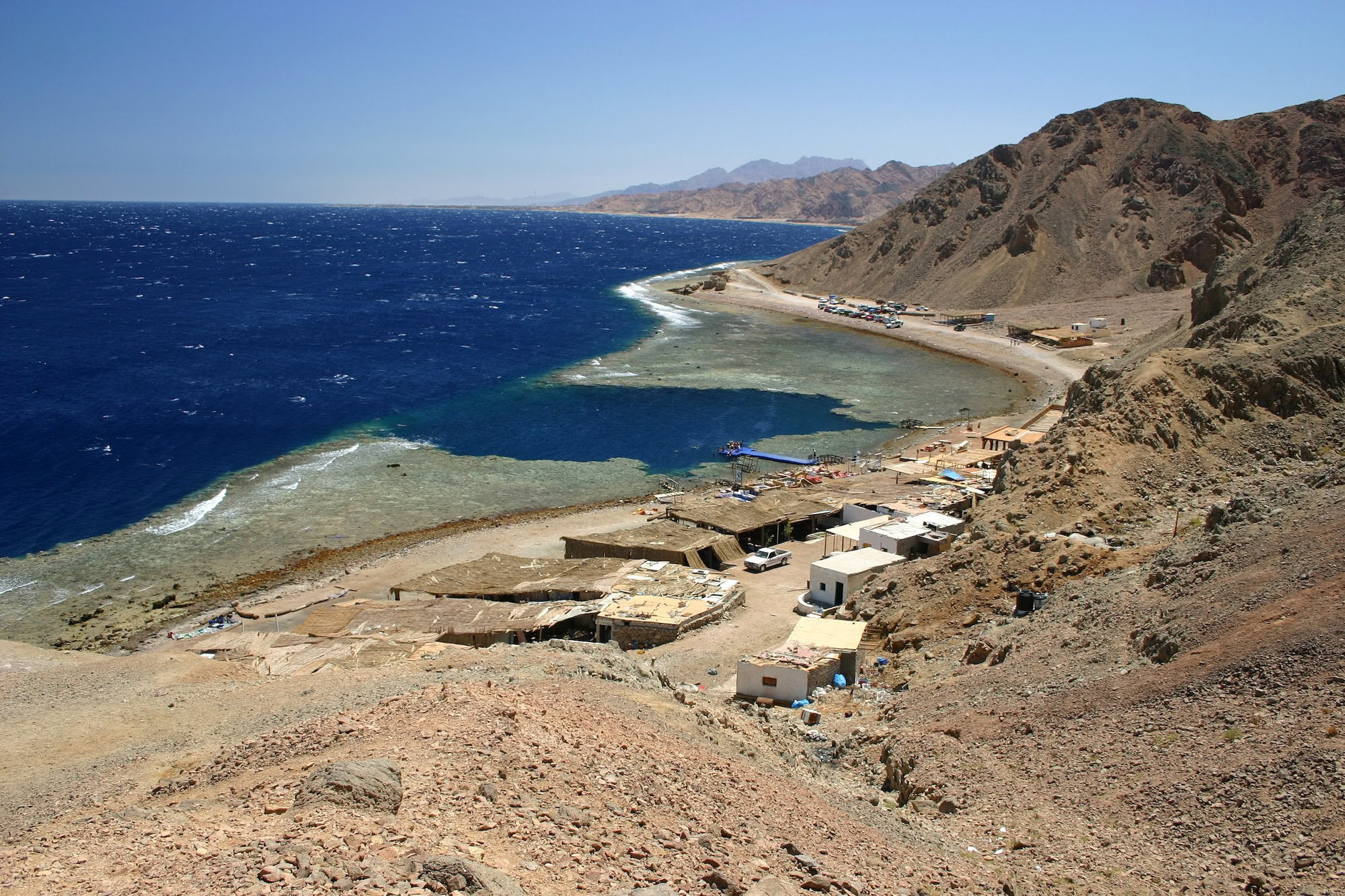Blue Hole diving site at Red Sea coast with coral reef and boats