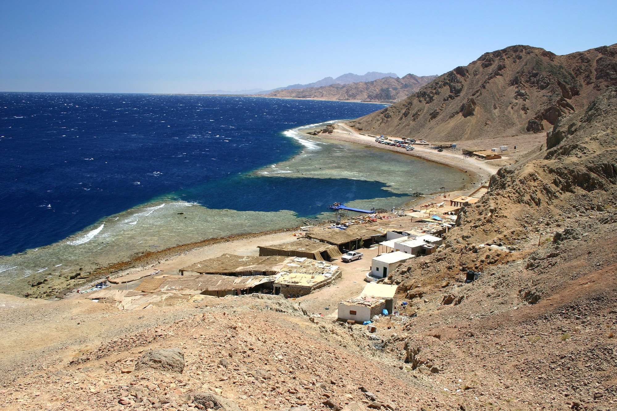 Blue Hole diving site in Dahab with traditional beachfront buildings and boats along Red Sea coast