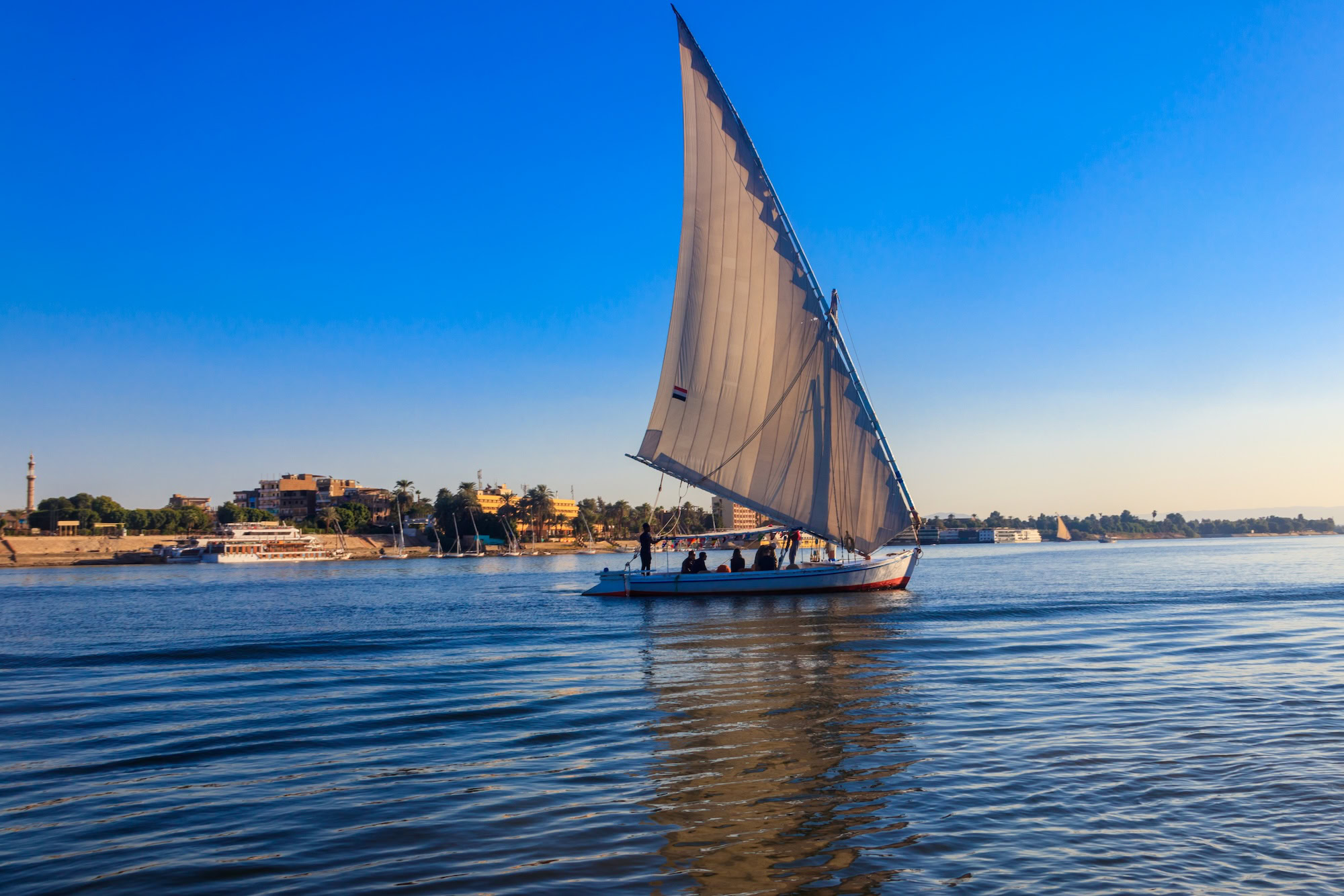 Traditional felucca sailboat with triangular sail on the Nile River at sunset
