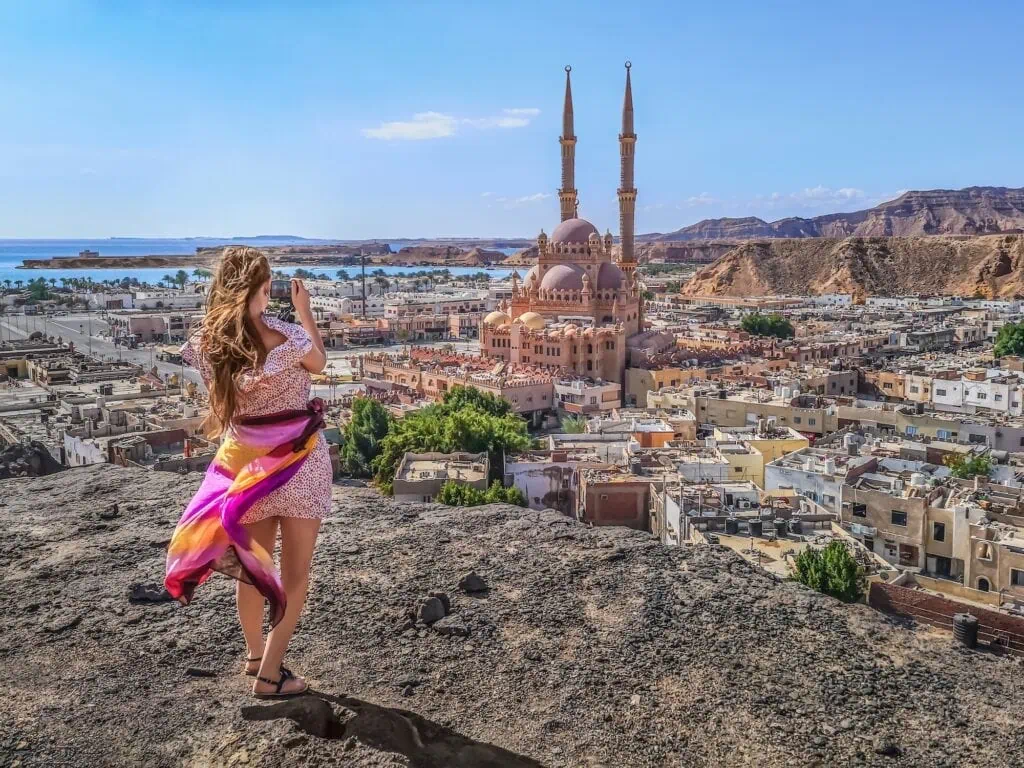 A woman seen from behind photographing the mosque and surrounding cityscape from an elevated viewpoint, Al Sahaba Mosque, Sharm El Sheikh