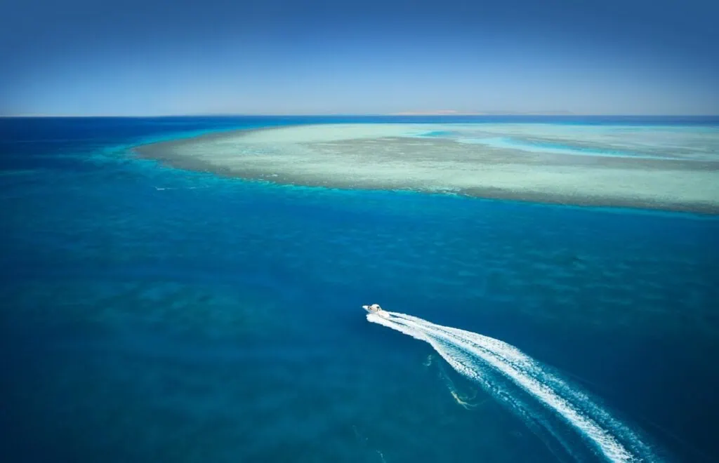 Speedboat crossing clear blue waters near a shallow reef off El Gouna