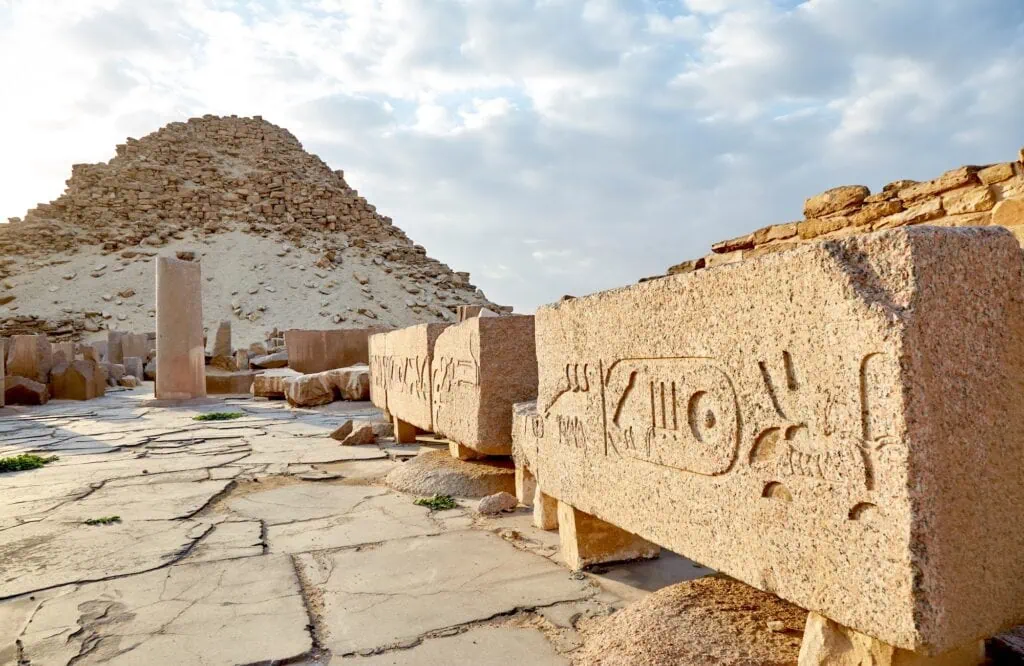 Granite blocks carved with hieroglyphs and pyramid ruins at the Abusir Pyramids Complex, Cairo
