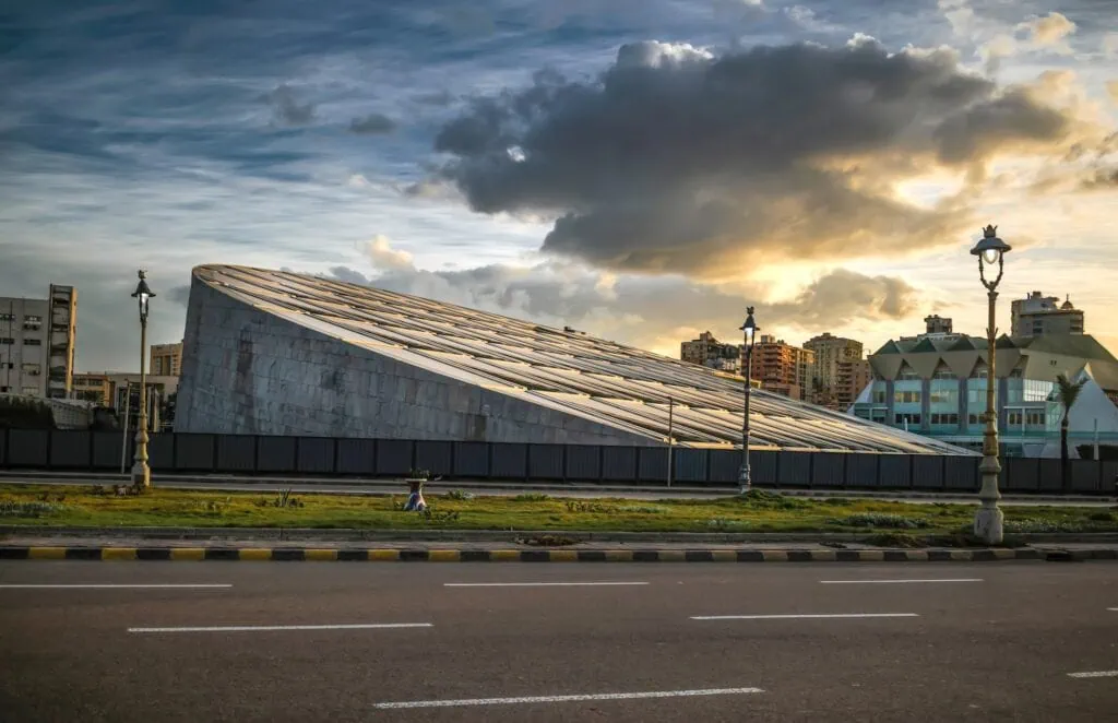 Sunset view along the street beside the Bibliotheca Alexandrina with coastal roadway and buildings, Alexandria