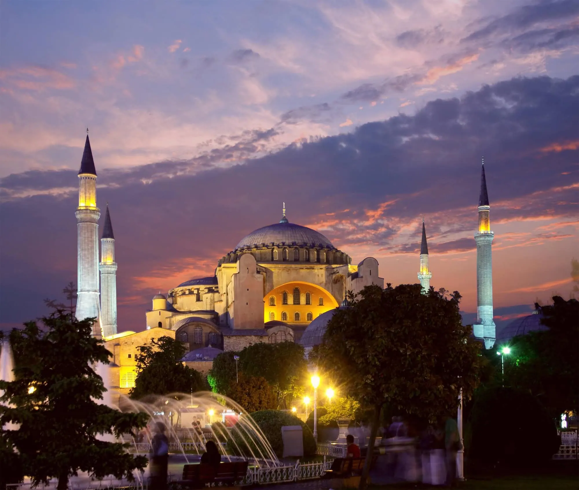 Hagia Sophia mosque illuminated at sunset with dramatic pink sky and fountain