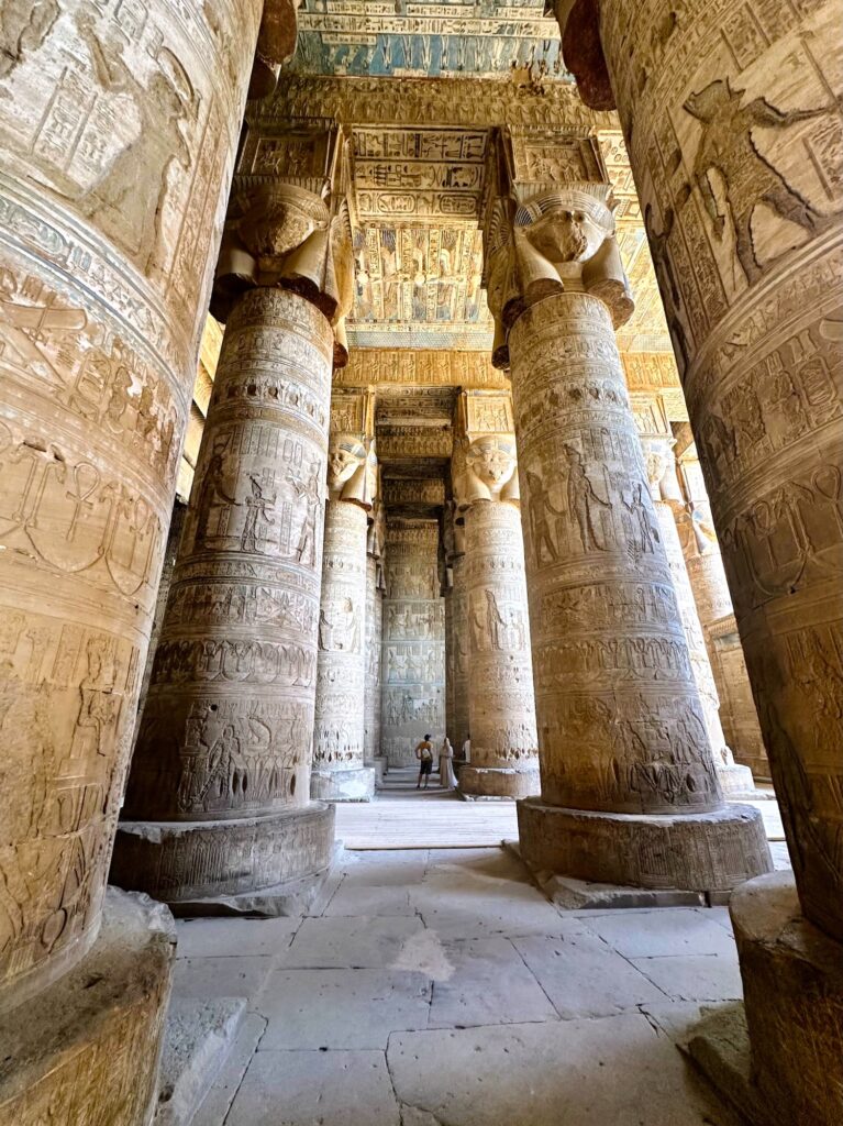Hathor-headed columns covered with carved reliefs inside the hypostyle hall of Dendera Temple, Dendera