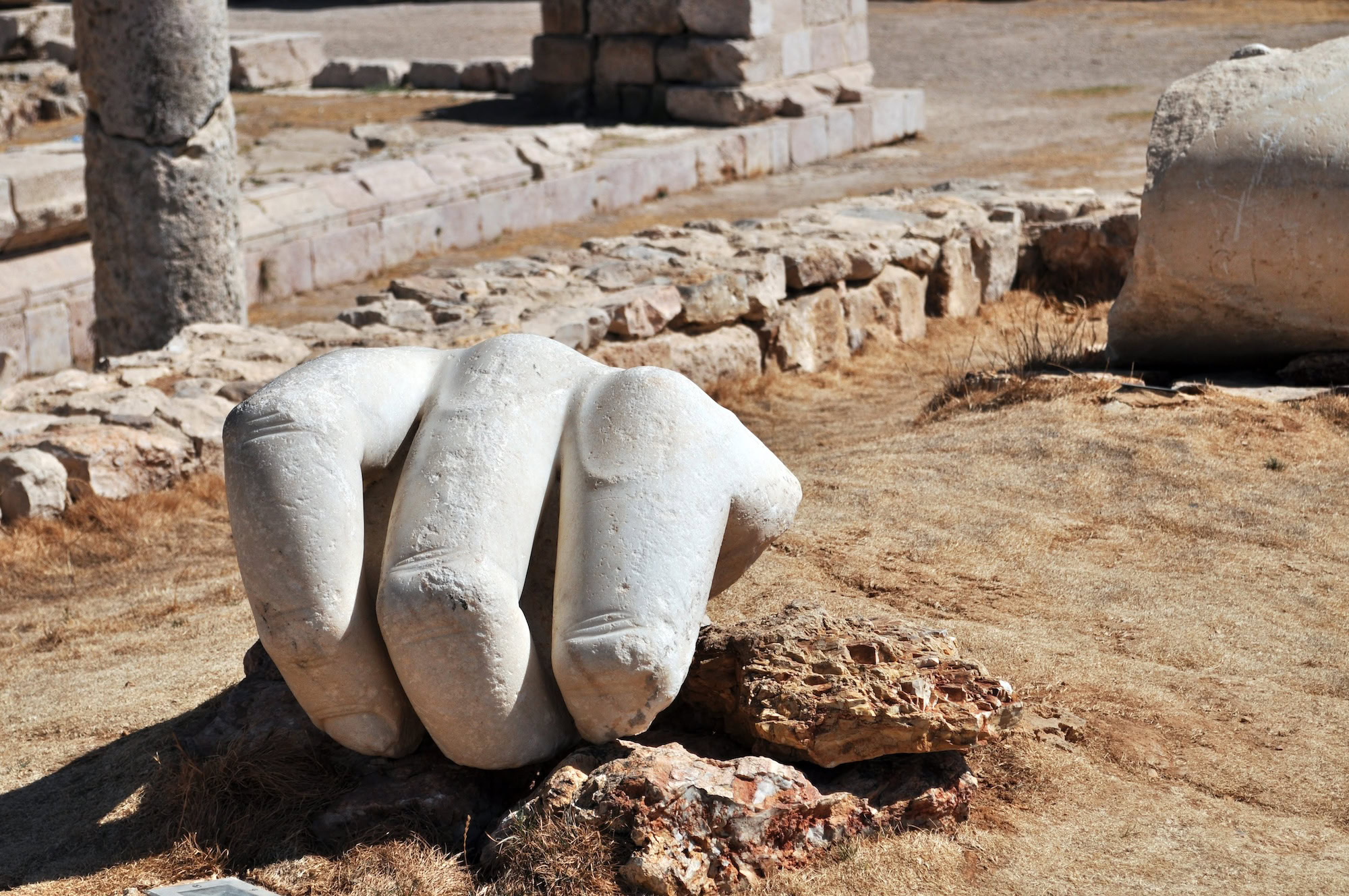 Ancient Roman ruins featuring marble hand sculpture and classical stone columns at archaeological site