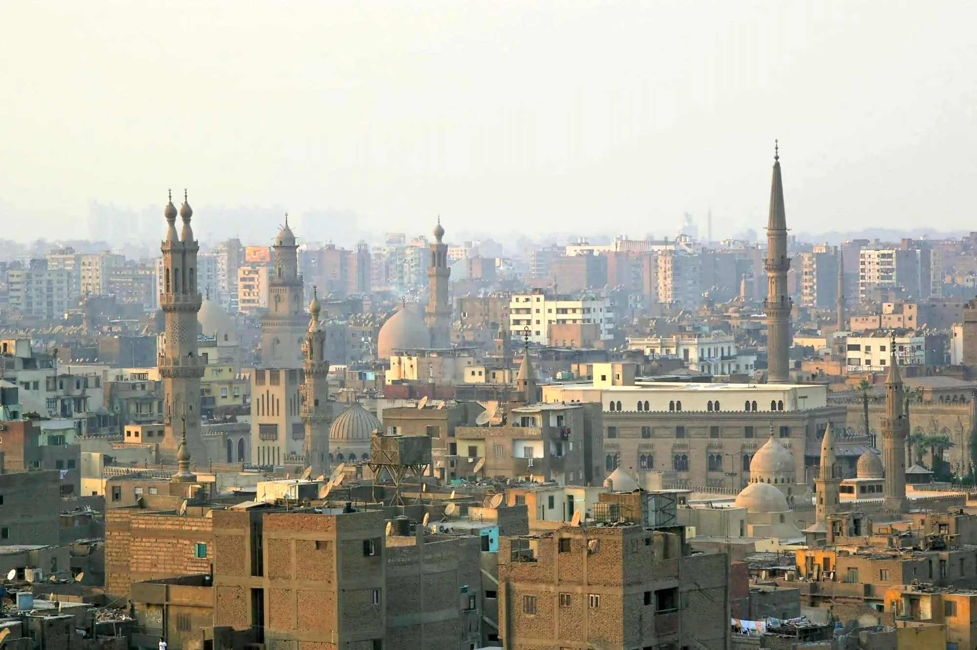 Golden sunset view of Islamic Cairo with minarets and traditional architecture in atmospheric haze