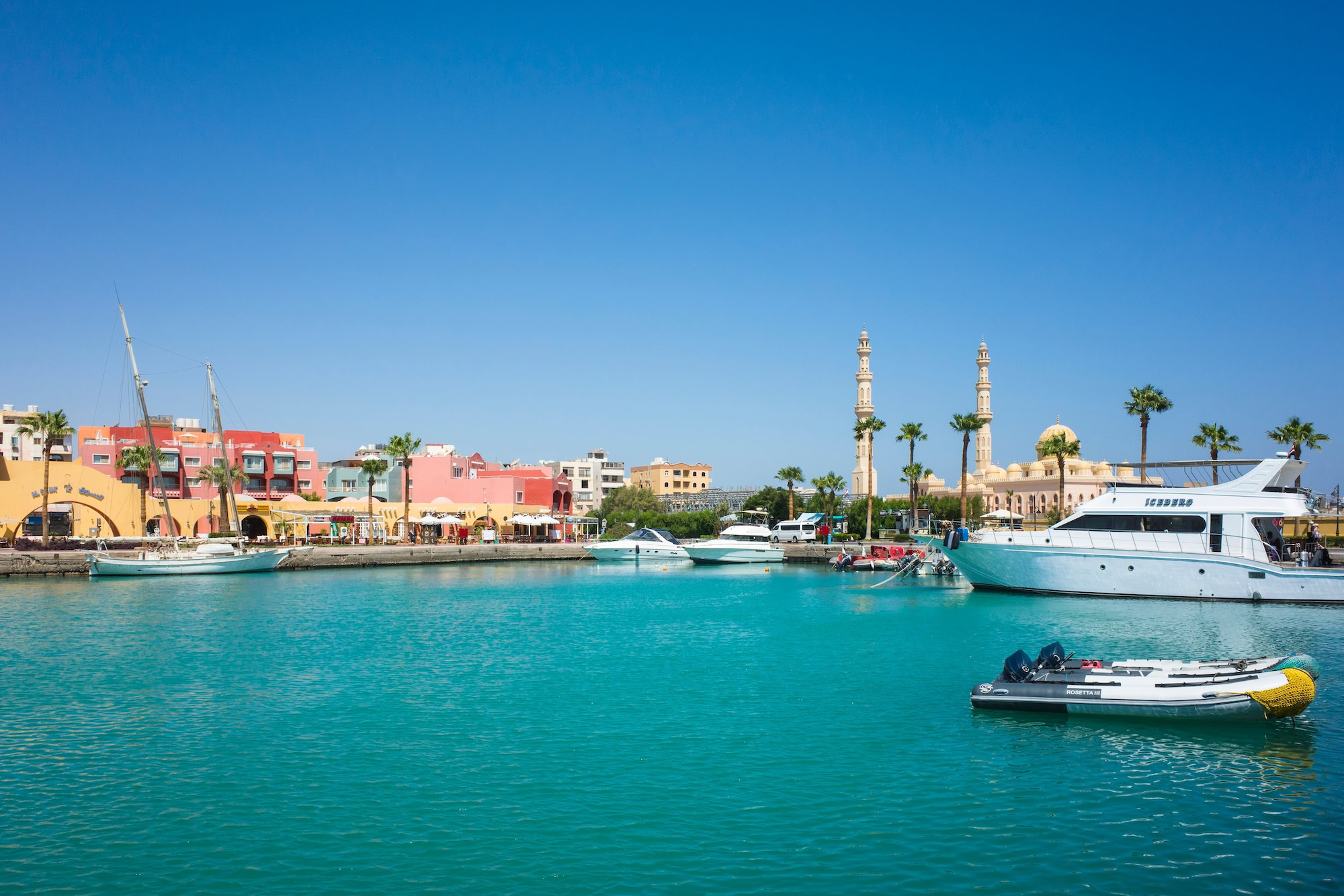 Luxury marina in Hurghada with turquoise waters, colorful waterfront buildings, yachts, and El-Mina Mosque