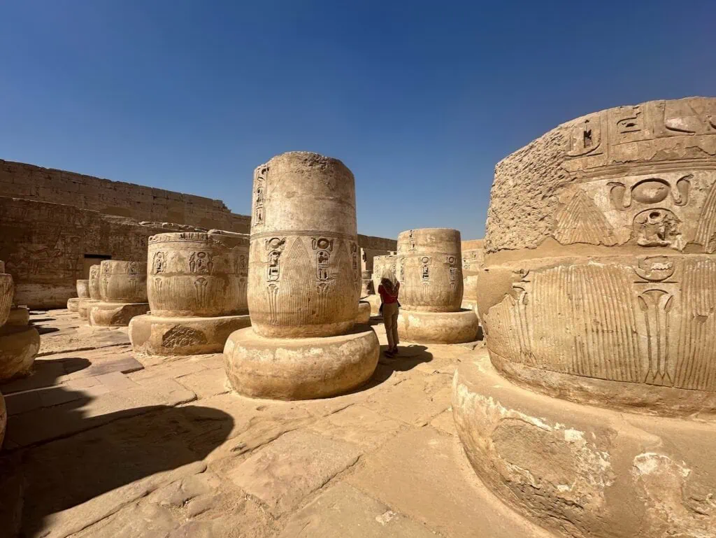 Stone column bases with carved hieroglyphs arranged in an open courtyard at the Medinet Habu temple complex, Luxor