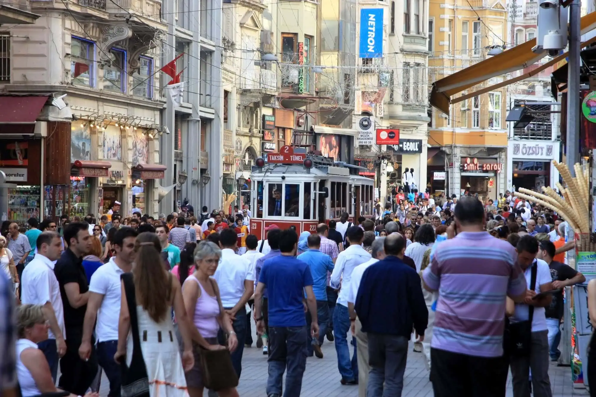 Bustling street scene in Istanbul's Taksim area with vintage tram, shops, and crowds of people