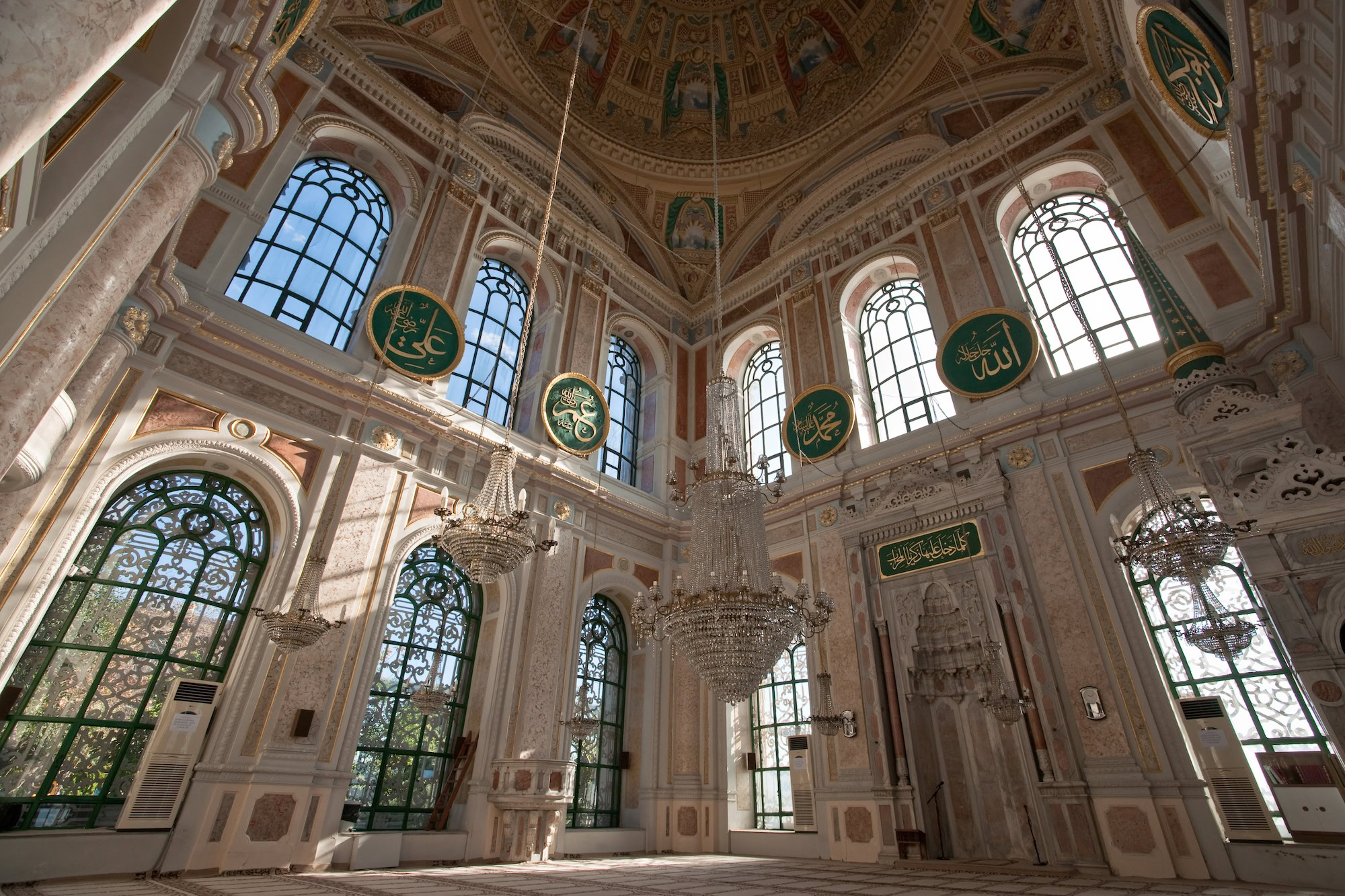 Interior view of Hagia Sophia showing massive dome, chandeliers, marble columns and Islamic calligraphy