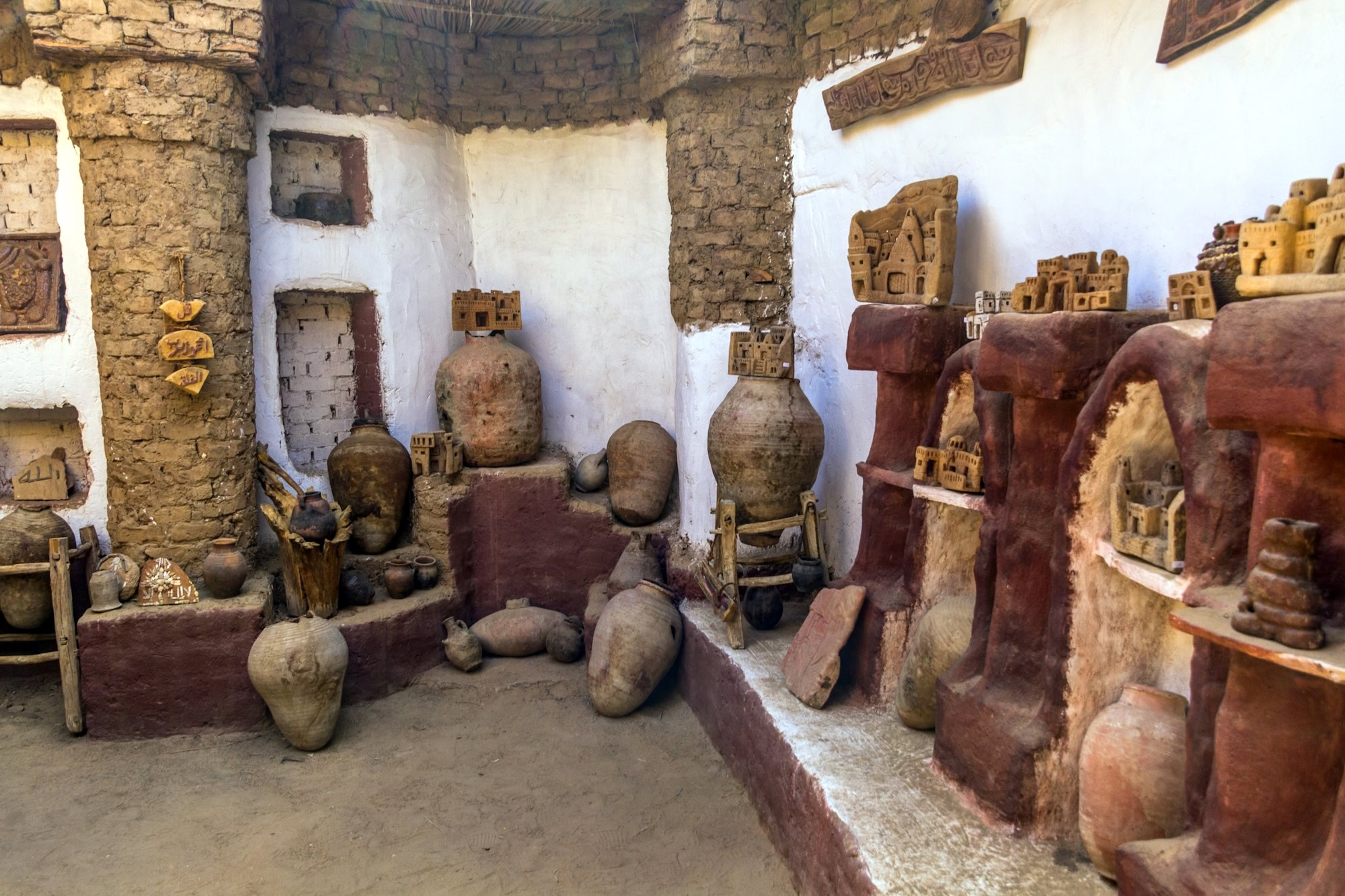 Traditional pottery workshop with clay vessels and decorative tiles displayed on stone shelves