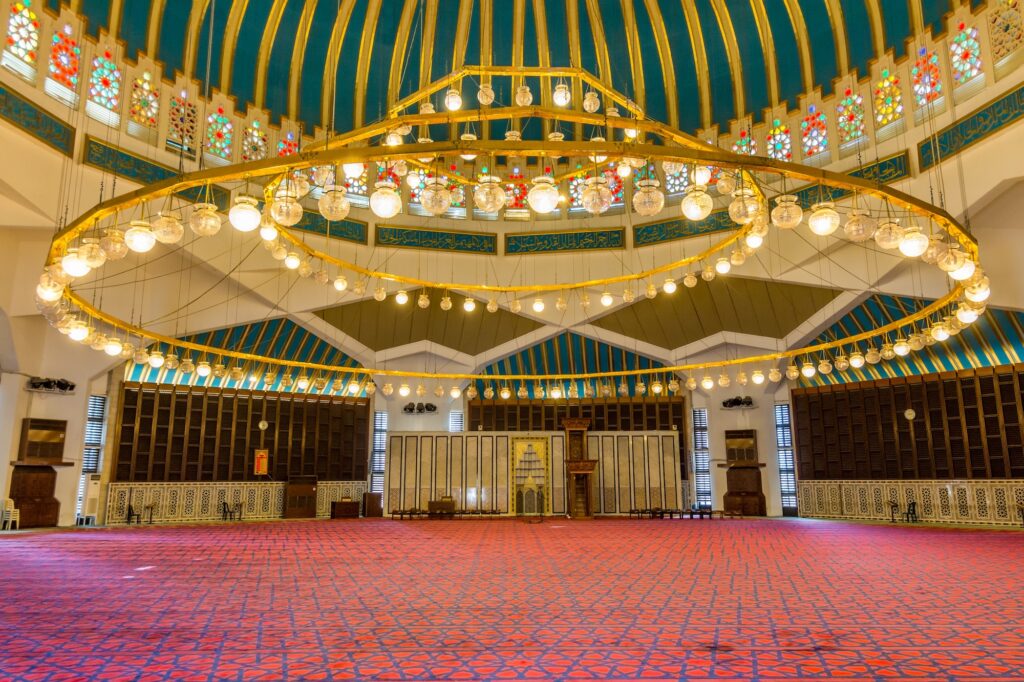 Interiors of King Abdullah Mosque with red Arabic traditional carpet in Amman Jordan