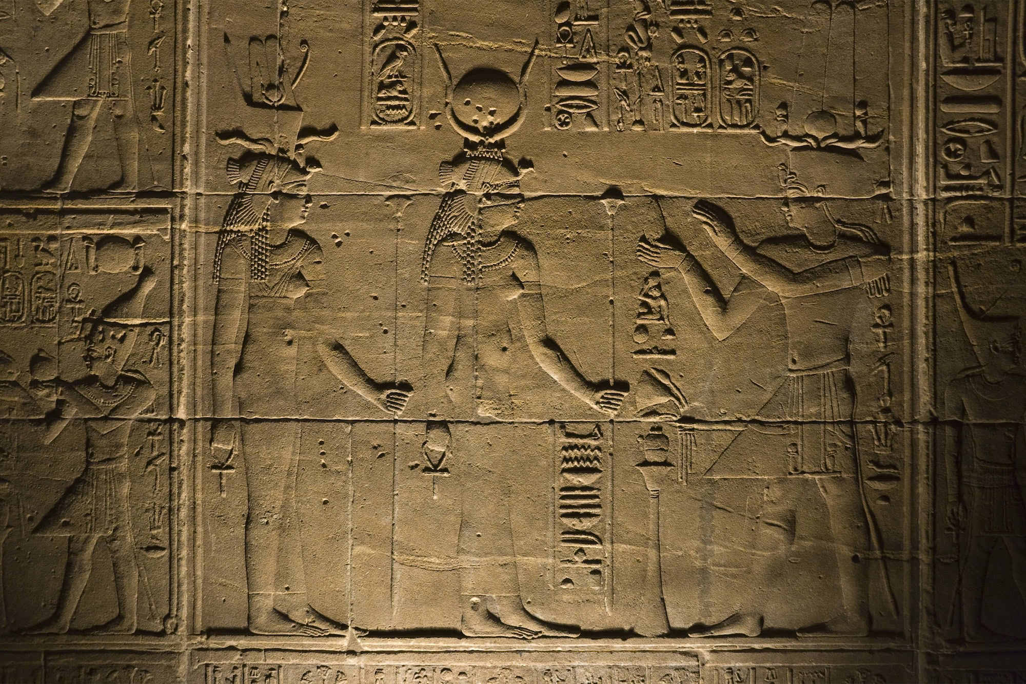 Jeroglíficos egipcios antiguos tallados en pared de piedra con figuras de deidades