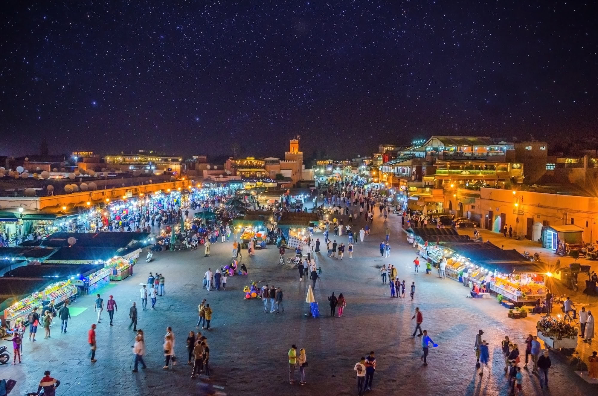 Nighttime view of Jemaa el-Fnaa square in Marrakech with food stalls, crowds, and mosque tower