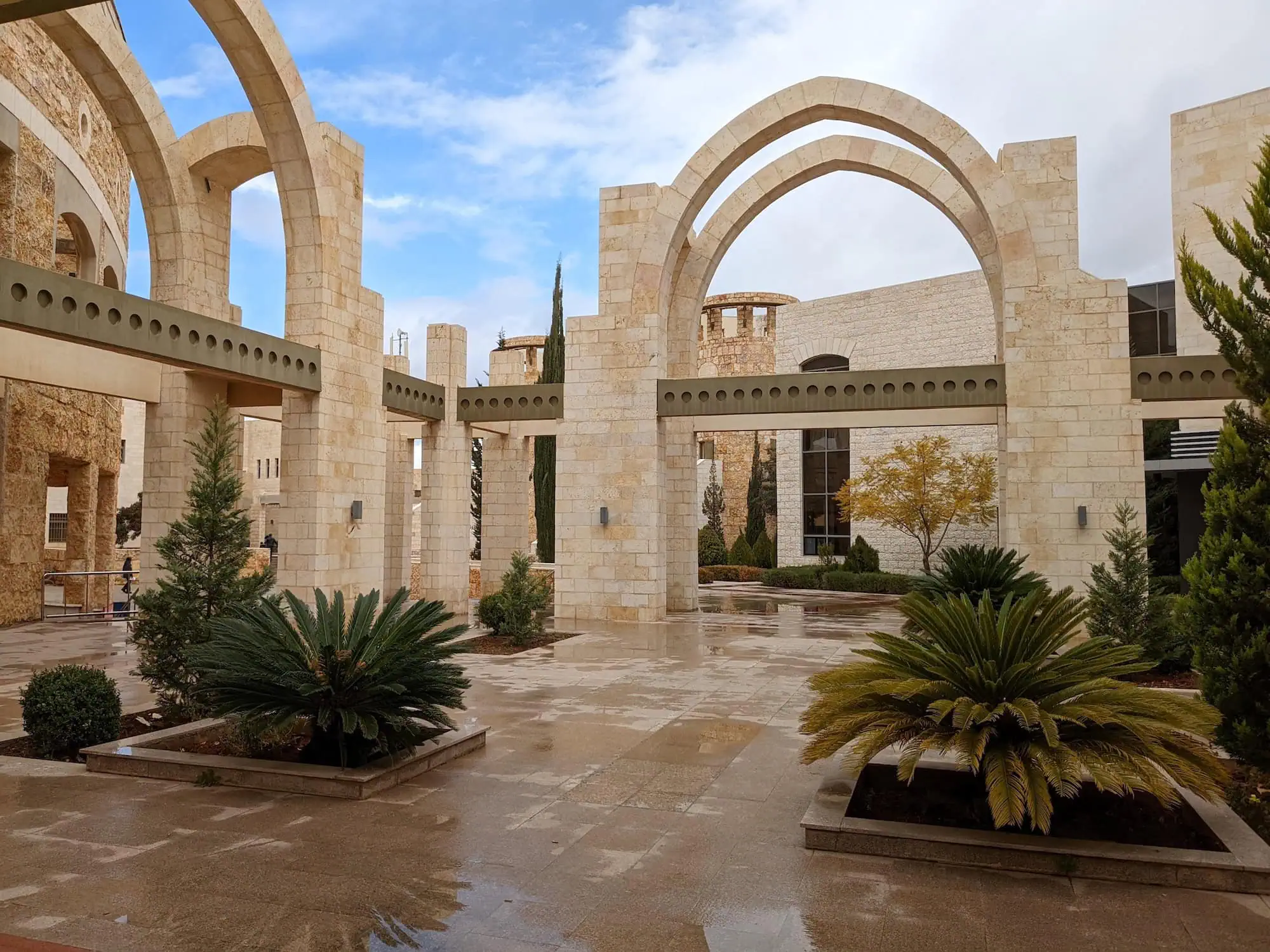 Modern university campus with arched stone buildings and palm trees in Jordan