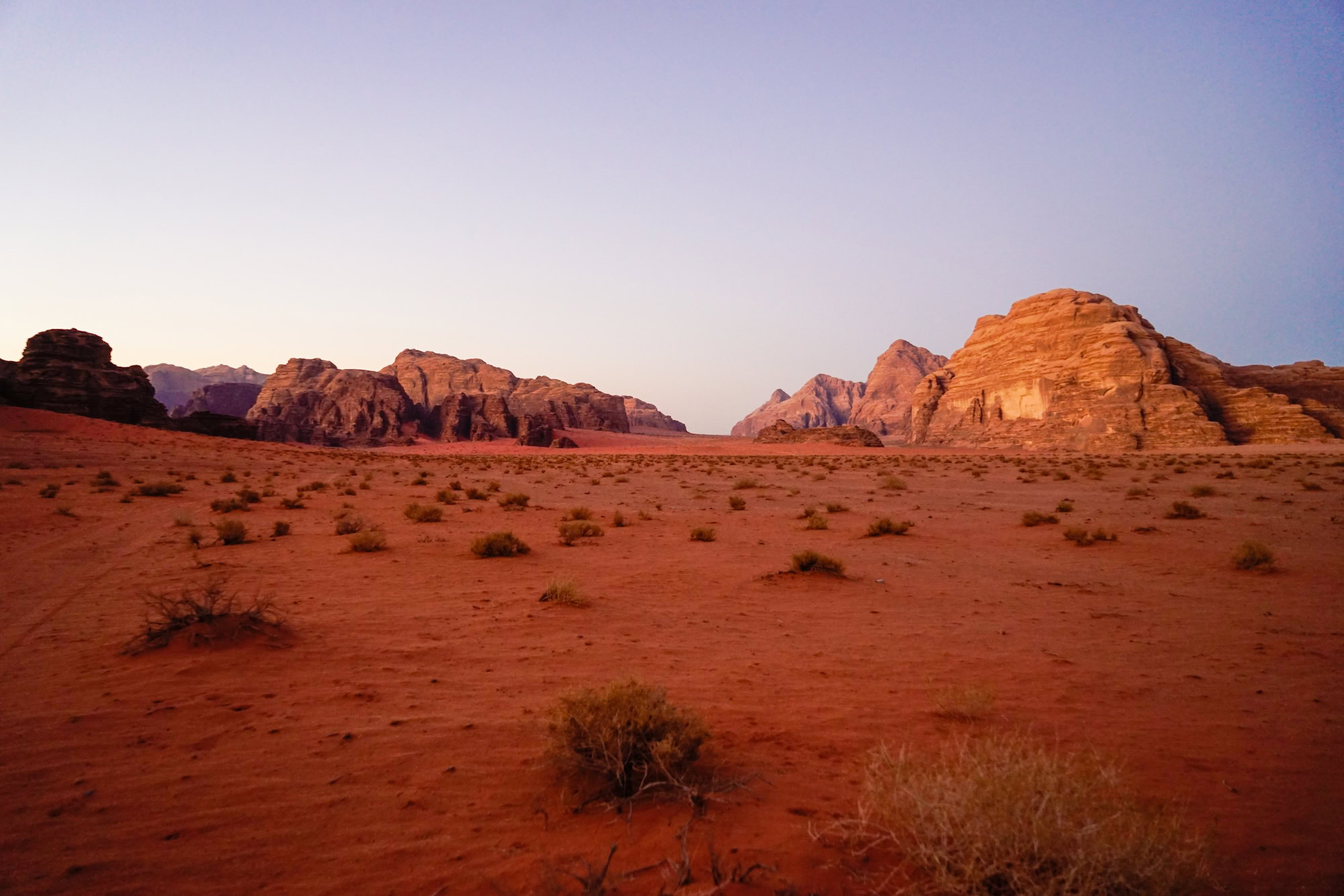 Desert landscape in Wadi Rum showing red sandstone formations during golden sunset hour