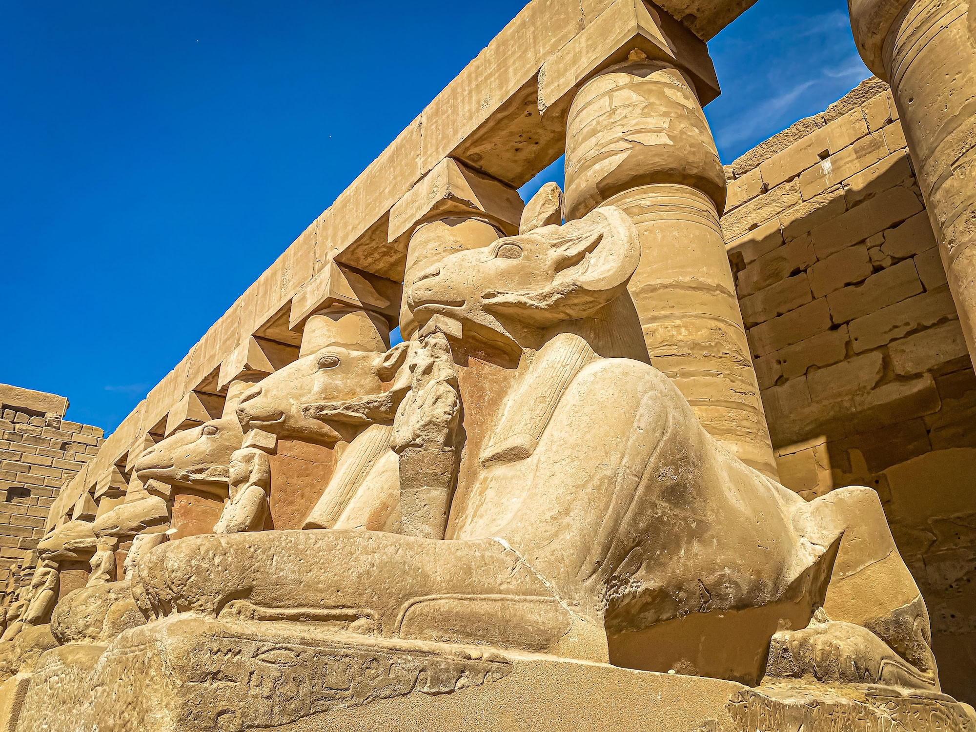 Ram-headed sphinx statues and ancient columns at Karnak Temple Complex in Luxor, Egypt